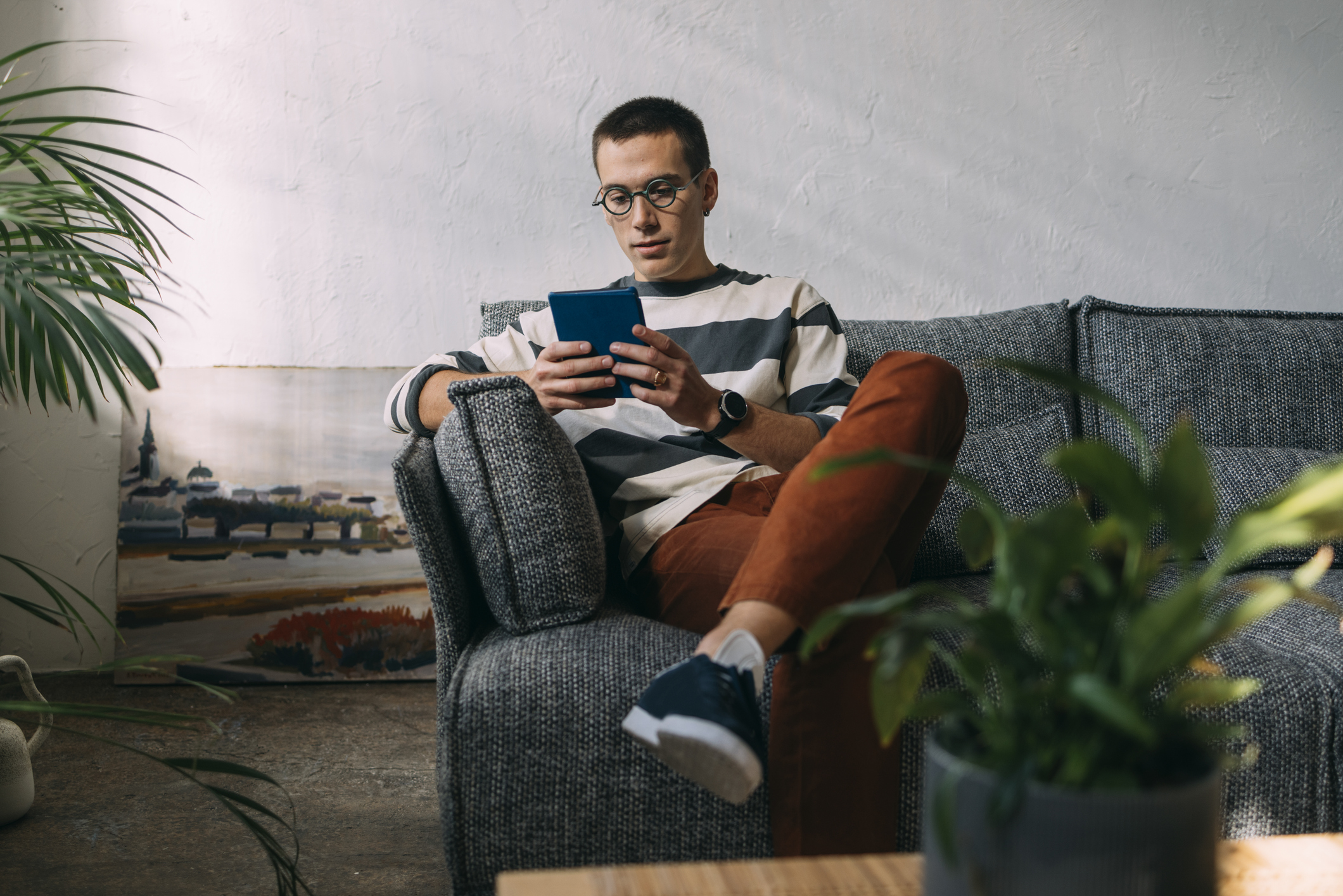 Actor portrayal of a person sitting on a couch living with hemophilia, surrounded by text explaining how hemophilia can affect daily life.